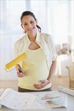 Pregnant woman holding a paint roller.