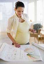 Pregnant woman looking at house plans.