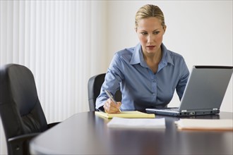 Businesswoman working at conference table.