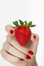 Hand holding red strawberry.