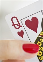 Hand holding a queen of hearts card.