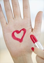 Red heart drawn on hand with lipstick.