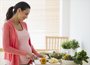 Pregnant woman making salad.