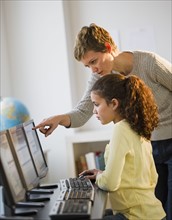 Teacher helping student in computer lab.