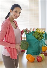 Pregnant woman unpacking groceries.