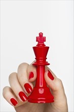 Hand holding red king chess piece.