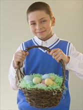 Young boy holding a basket of Easter eggs.