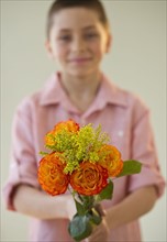 Young boy holding a bouquet of roses.