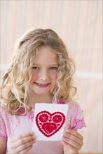 Young girl holding a Valentine card.