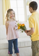 Young boy giving flowers to young girl.
