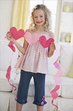 Young girl holding heart cut outs.