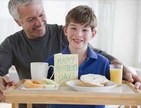Father and son bring mom breakfast in bed. Photographe : Jamie Grill