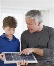Father showing solar panel to son. Photographe : Jamie Grill