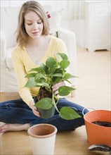 Woman replanting a houseplant. Photographe : Jamie Grill