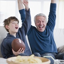 Father and son watching football game. Photographe : Jamie Grill