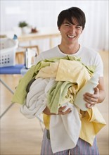Man holding pile of laundry. Photographe : Daniel Grill
