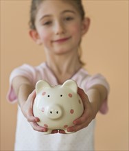 Young girl holding a piggy bank. Photographe : Daniel Grill
