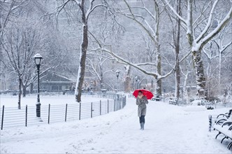 Woman walking with red umbrella on a snowy day. Photographe : Daniel Grill
