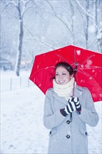 Woman walking with red umbrella on a snowy day. Photographe : Daniel Grill