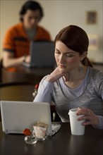 Woman working on laptop in coffee shop. Photographe : Daniel Grill