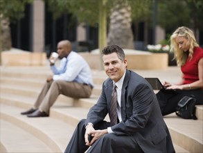 Business people sitting on outdoor steps.
