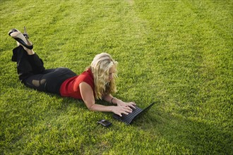 Woman working on laptop outdoors.
