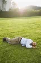 Businessman napping on lawn.