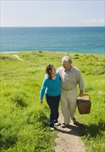 Couple carrying picnic basket to the beach.