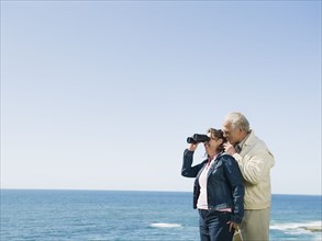 Couple looking at ocean with binoculars.