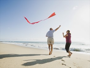 Couple flying kite on beach.