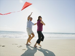 Couple flying kite on beach.