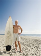 Man holding surfboard on beach.