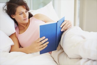 Woman reading in bed. Photographe : momentimages