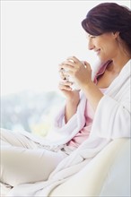 Woman in bathrobe drinking coffee. Photographe : momentimages