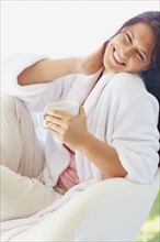 Woman in bathrobe drinking coffee. Photographe : momentimages