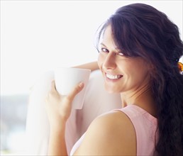 Relaxed woman drinking coffee. Photographe : momentimages