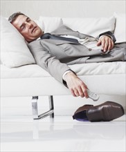 Businessman napping on couch. Photographe : momentimages