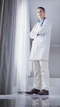 Doctor standing in front of window. Photographe : momentimages
