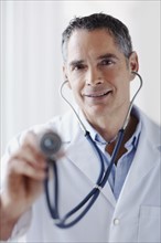 Doctor holding stethoscope. Photographe : momentimages