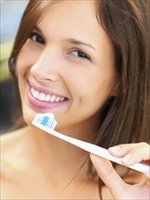 Woman holding a toothbrush. Photographe : momentimages