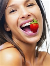 Woman eating strawberry. Photographe : momentimages