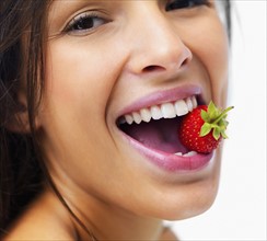 Woman eating strawberry. Photographe : momentimages