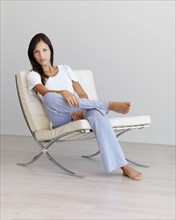 Relaxed woman sitting on modern chair. Photographe : momentimages