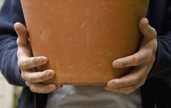 Hands holding clay pot. Photographe : Stewart Cohen