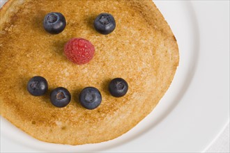 Pancake with smiley face made from blueberries and raspberry. Photographe : Kristin Lee