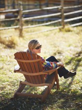Woman sitting in Adirondack chair. Photographe : John Kelly