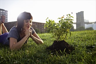 Woman looking at aspen sapling on grass. Photographe : Shawn O'Connor