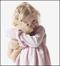 Young girl hugging teddy bear. Photographe : Mike Kemp