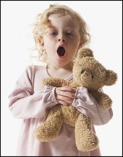 Tired young girl holding teddy bear. Photographe : Mike Kemp