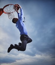 Businessman playing basketball. Photographe : Mike Kemp